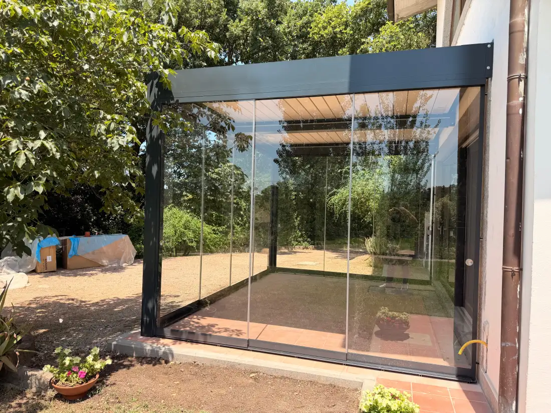 Glass veranda under a bioclimatic pergola, open to the garden