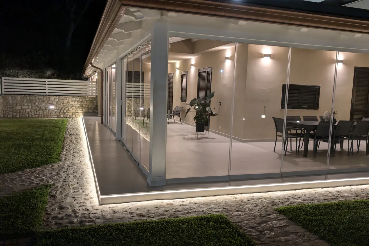Veranda enclosed with Sliding Floor sliding glazing, lit up in the evening