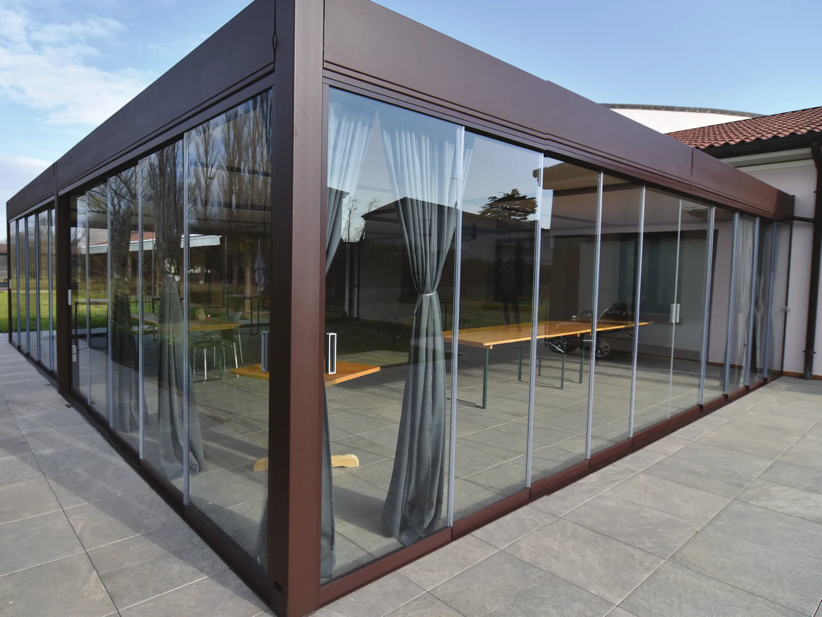 Sliding Floor with brown profiles enclosing a porch on three sides, on a stone floor