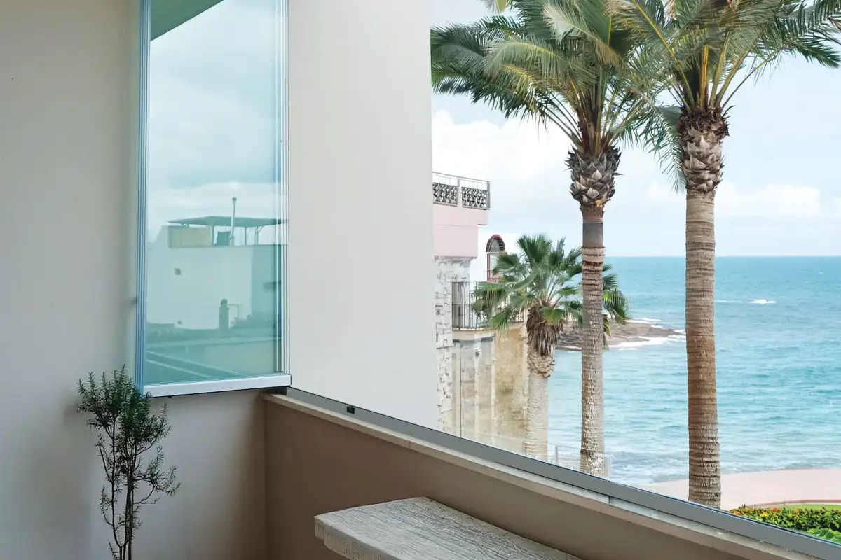 Seafront terrace with palm trees, enclosed by Libra glazing