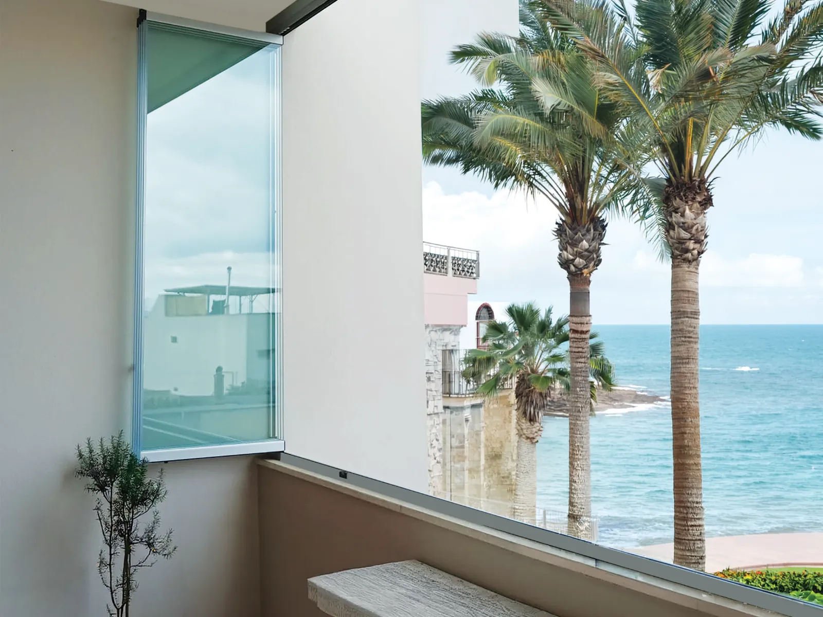 Libra chiude una loggia affacciata sul mare, con le palme oltre il vetro
