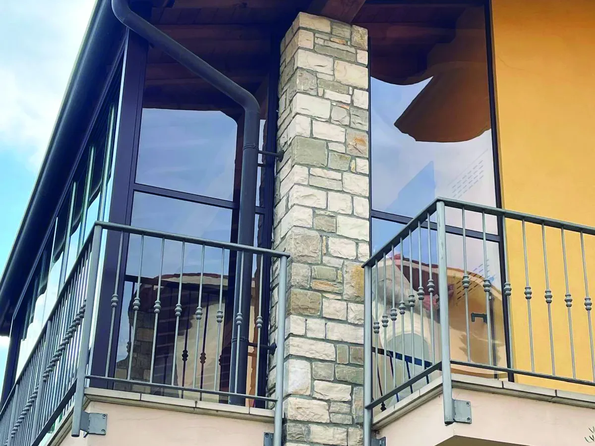 Libra chiude il balcone di una casa in pietra con ante in vetro trasparente