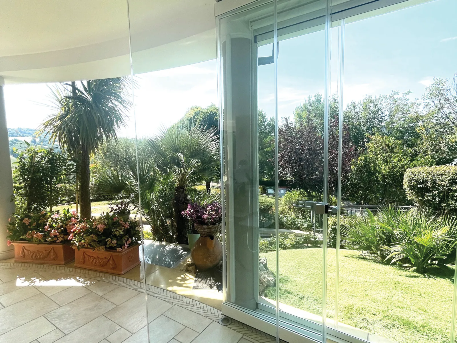 Parking glazing open onto a garden with palm trees